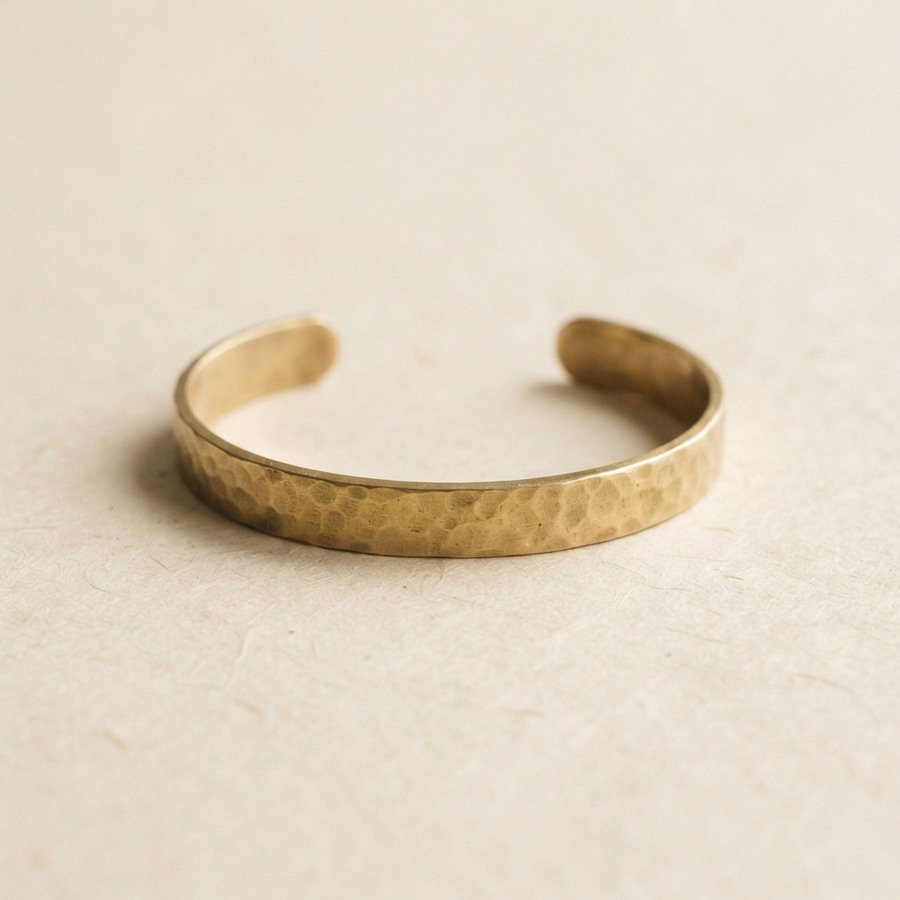 A hand-forged brass cuff bracelet with a hammered finish.